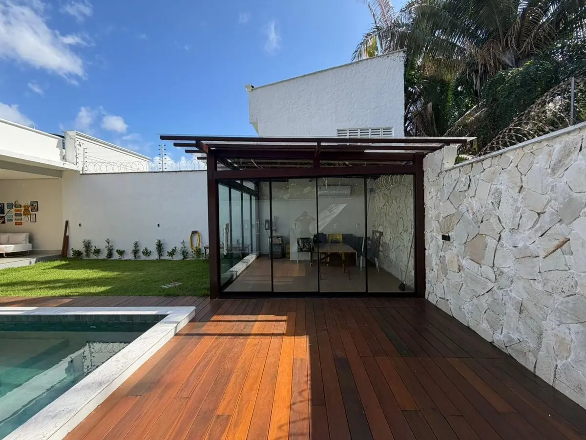 Pergolado em madeira com fechamento em vidro junto à piscina